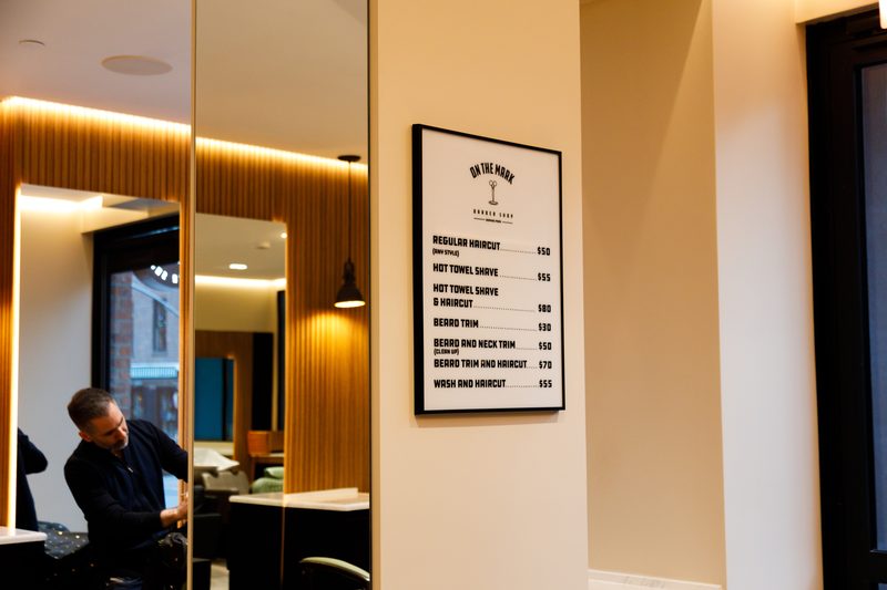 The price board and a barber at work in the mirror